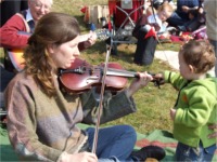 Kathleen O’Hara Farren plays a tune on the fiddle with the help of little Odhran Lafferty from Ballybrack.